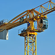 Yellow construction crane on building site showing cabin and counterweight, France